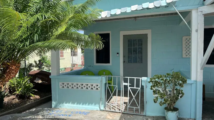 The blue cottage exterior, white porch gate and leafy front garden.