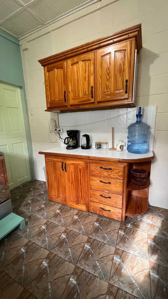 A kitchen counter with a kettle, cups and drinking water.