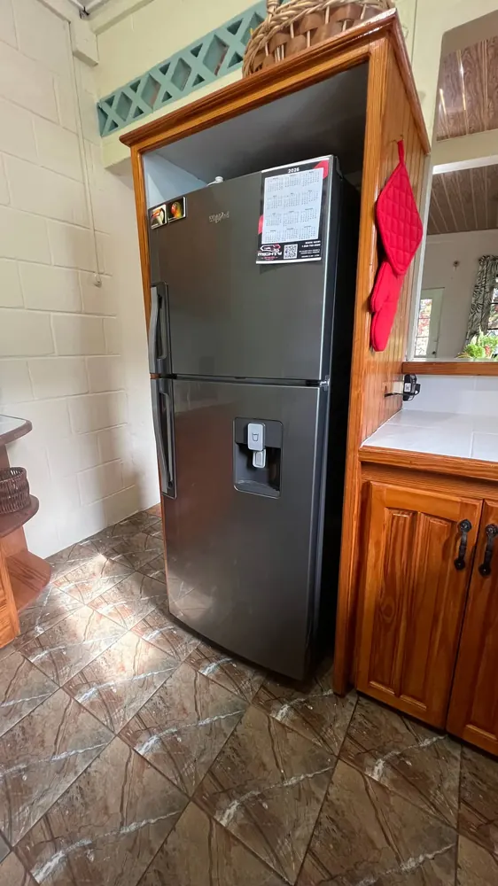 The refrigerator beside the timber kitchen cabinets.