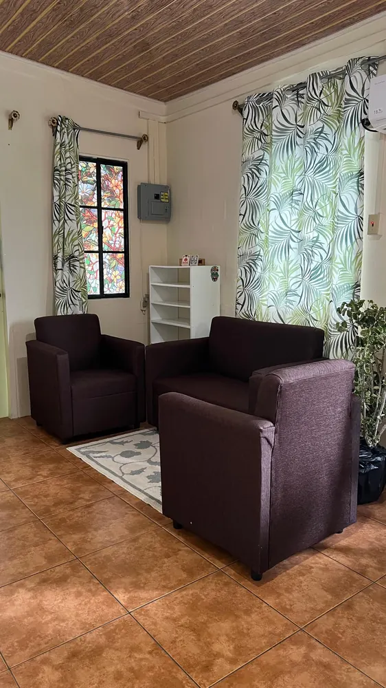 Lounge chairs, a coffee table and tropical leaf curtains in the living area.